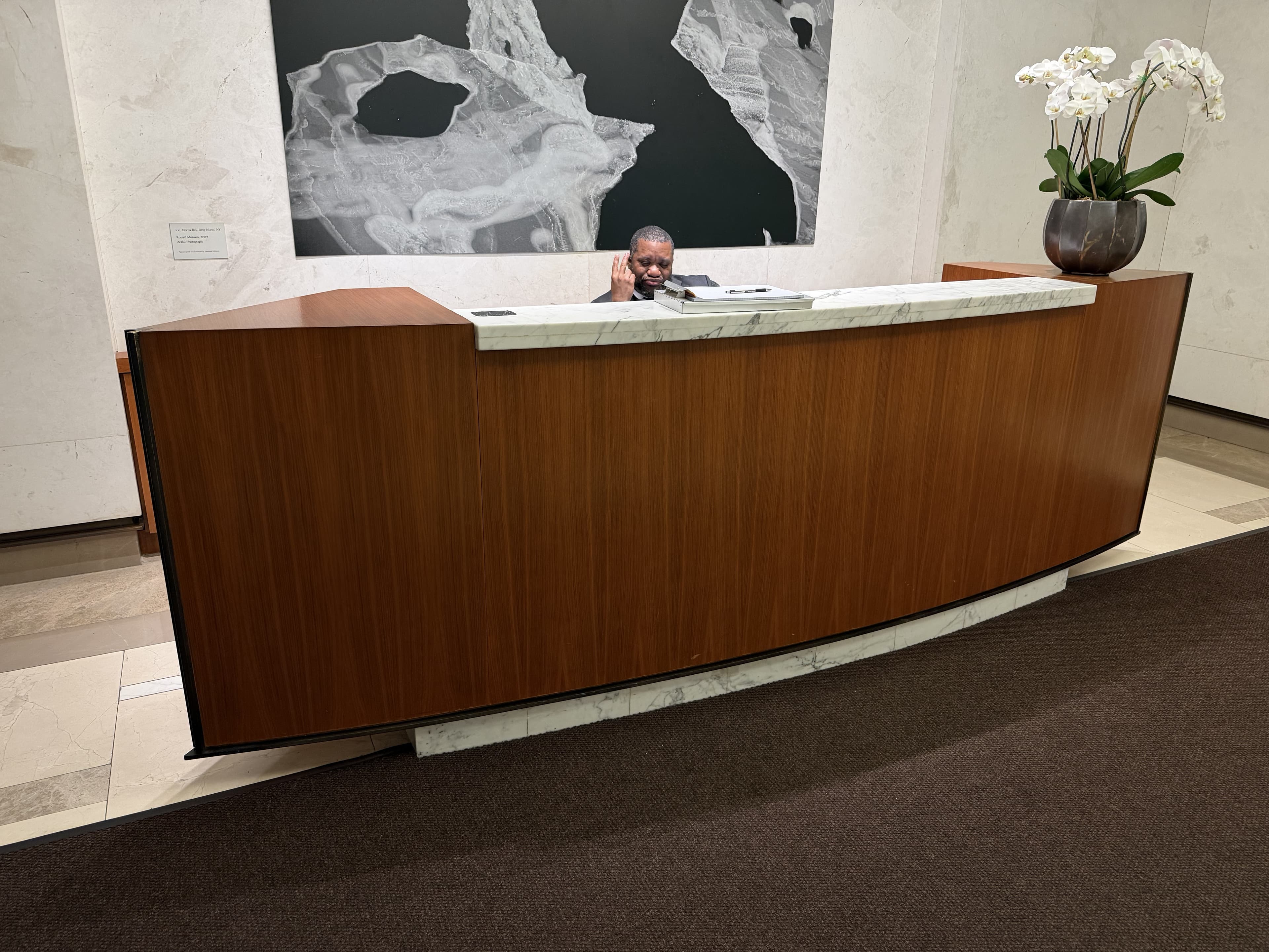 Finished curved veneer reception desk with marble top in a commercial lobby by Deerfield Interiors