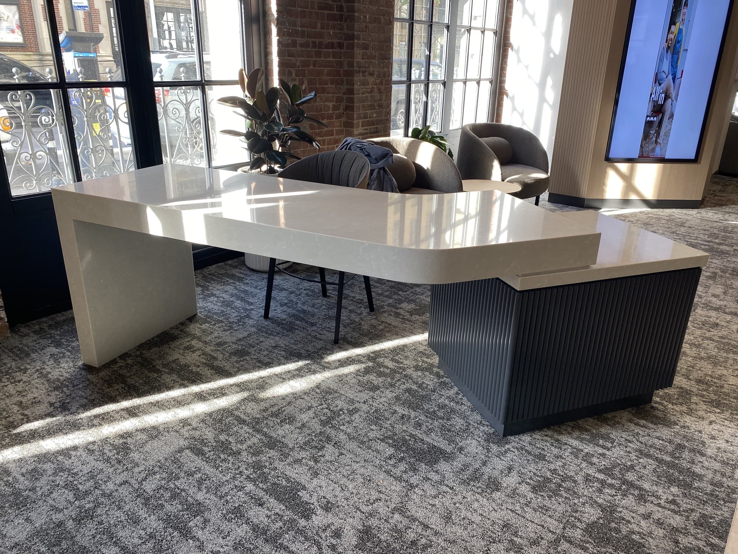 Finished stone waterfall console table and lounge in a custom commercial fit-out by Deerfield Interiors, New York City