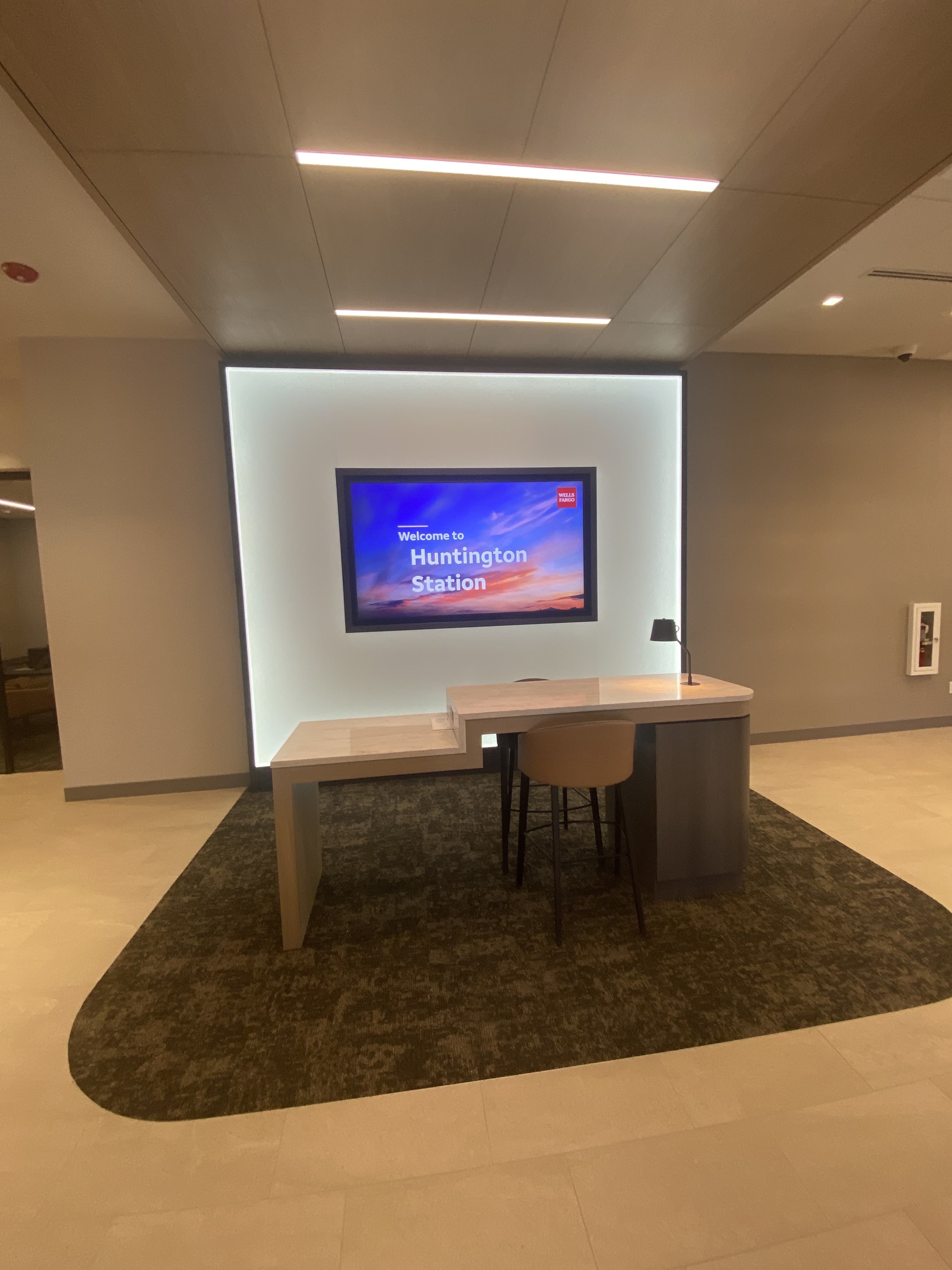 Finished bank welcome desk with backlit feature wall, built and installed by Deerfield Interiors on Long Island