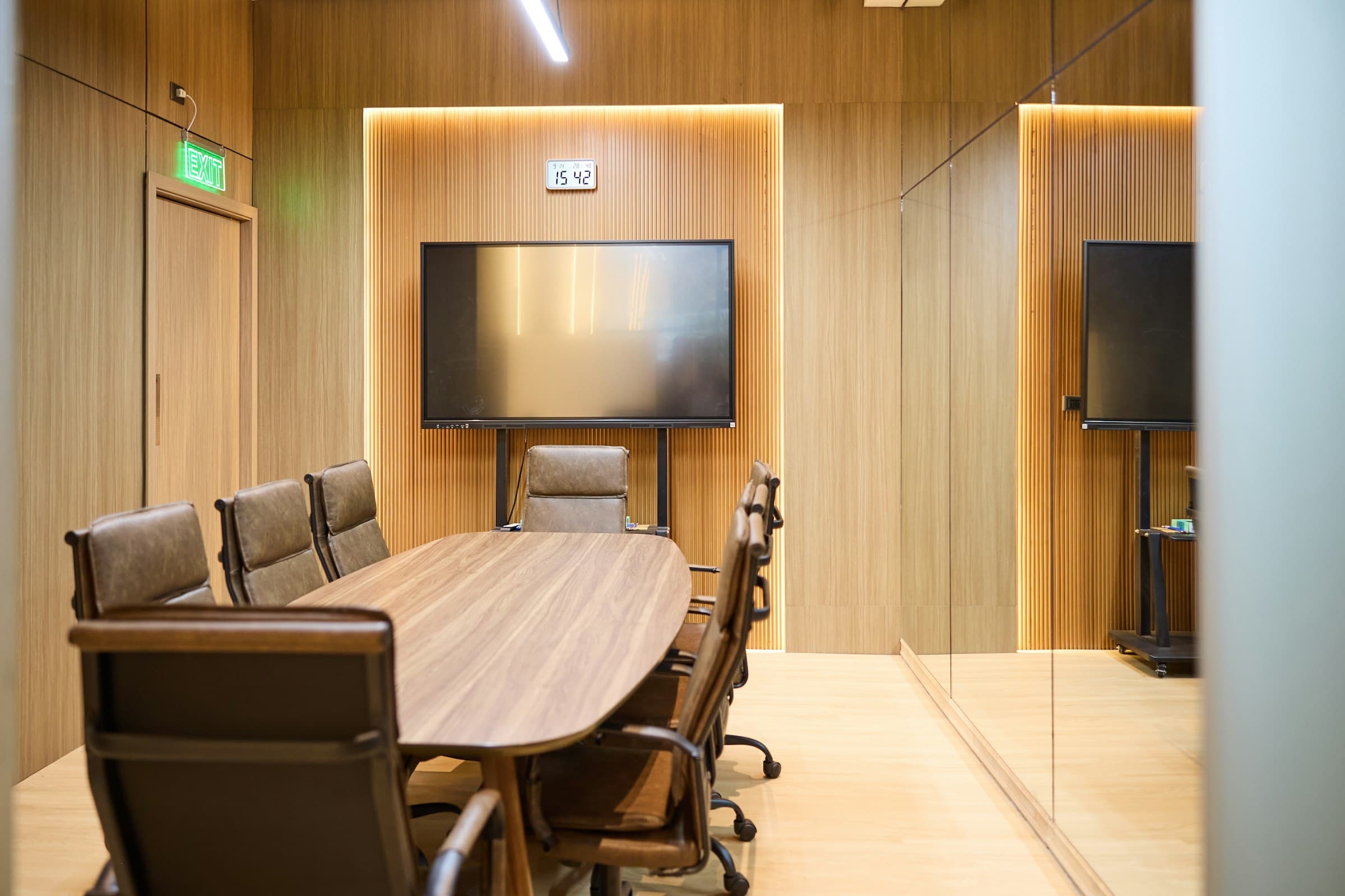Finished conference room with warm wood slat paneling and custom veneer table by Deerfield Interiors — serving the tri-state area