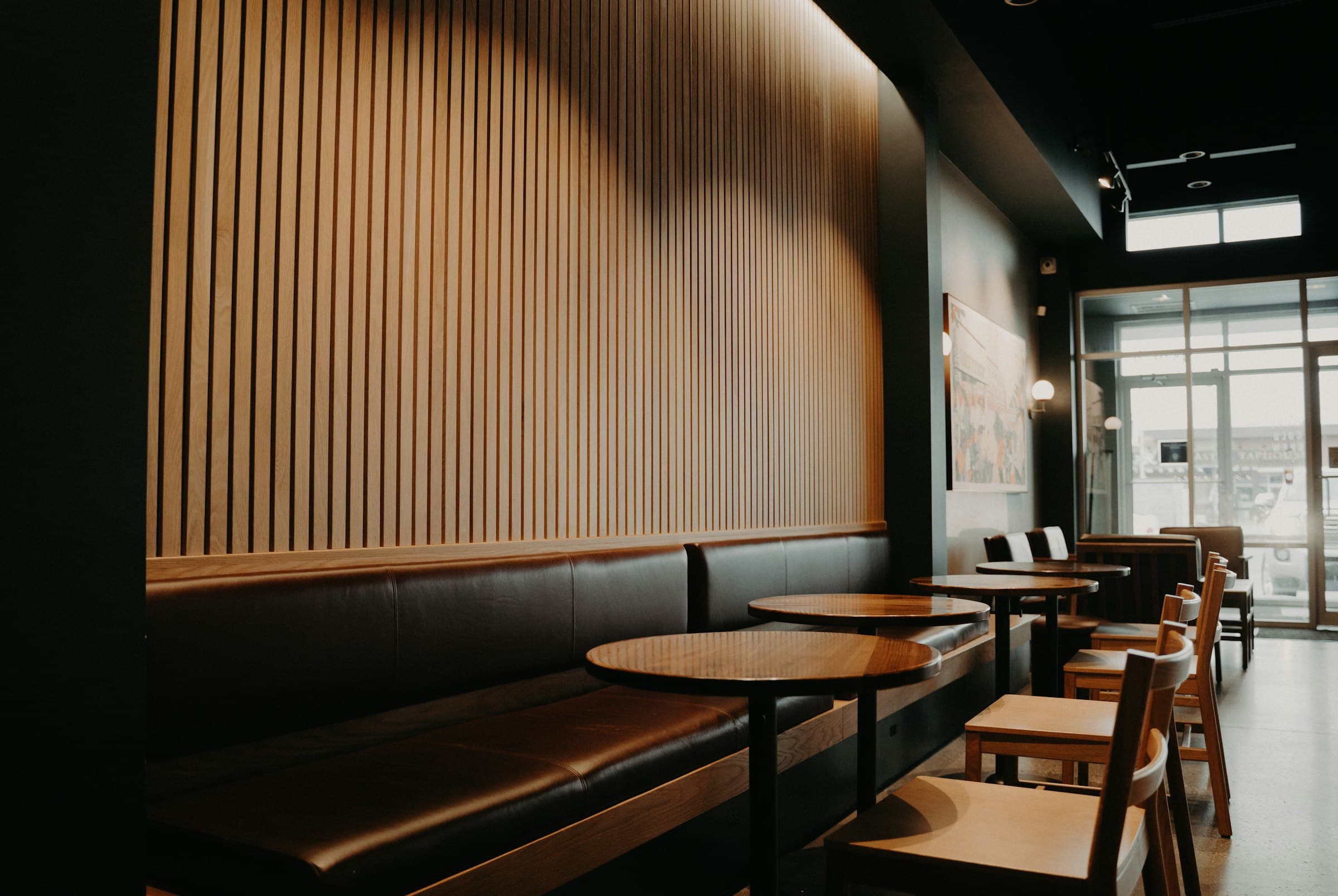 Finished restaurant interior with a walnut slat feature wall and leather banquette built by Deerfield Interiors, New York City